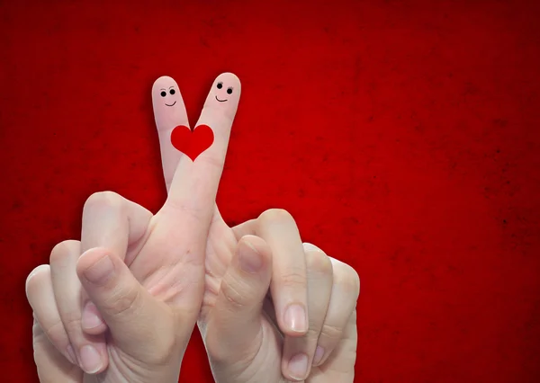 Two hands with fingers and a heart painted over a red paper vintage and grungy background — Stock Photo, Image