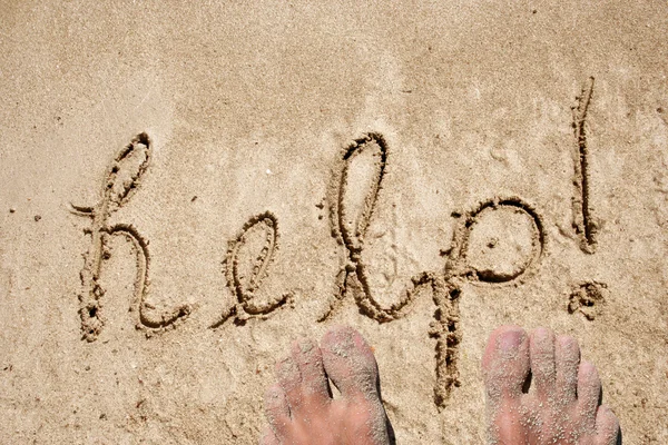 Konceptuella hjälptext handskrivna i sanden på en strand i en exotisk ö — Stockfoto