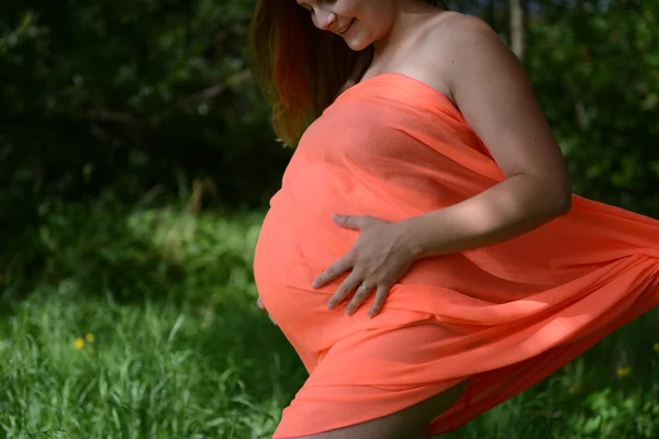 Молодая беременная женщина на лугу — стоковое фото