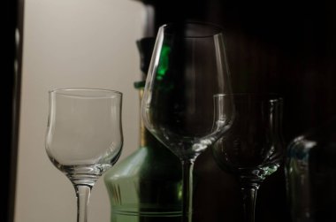 Şarap uzun cam bardaklar ve yeşil dekoratif eski içki şişesi cam ahşap vitrin.