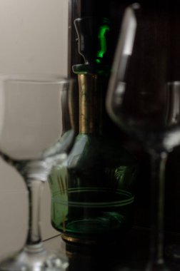 Şarap uzun cam bardaklar ve yeşil dekoratif eski içki şişesi cam ahşap vitrin.