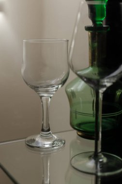 Şarap uzun cam bardaklar ve yeşil dekoratif eski içki şişesi cam ahşap vitrin.