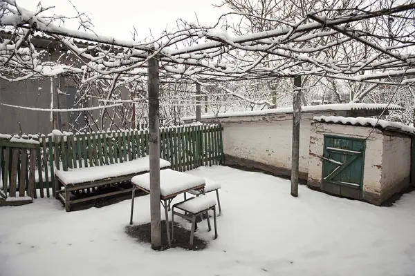 Snöiga landsbygdens innergård med hemmagjord bord, stolar och bänk — Stockfoto