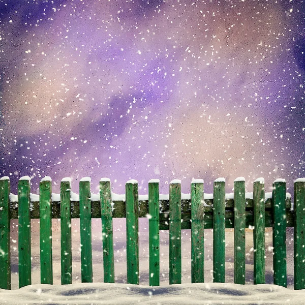 Besneeuwde oude groene houten hek en dalende sneeuw — Stockfoto