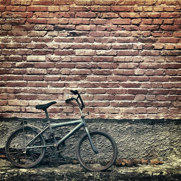Old rusty vintage bicycle leaning against a brick wall — Stock Photo, Image