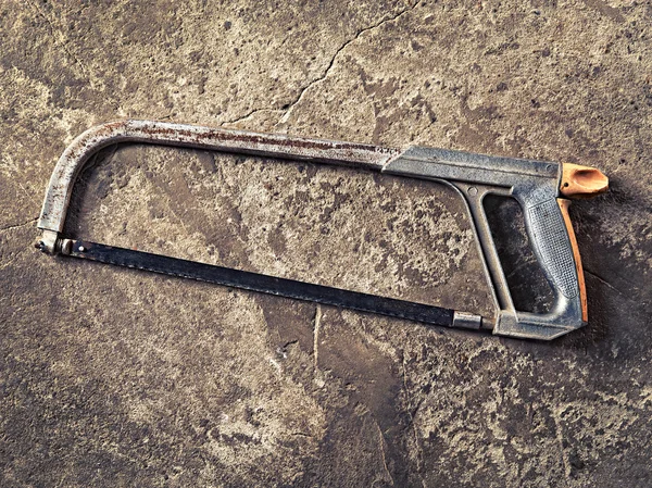 Old hacksaw on concrete grungy background — Stock Photo, Image