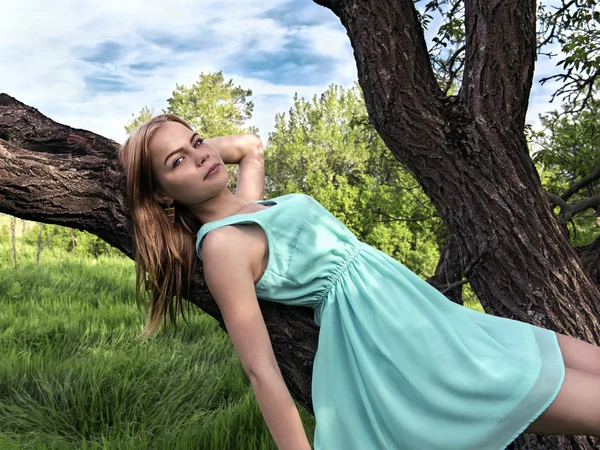 Young sensual blonde girl lying on a tree branch — Stock Photo, Image