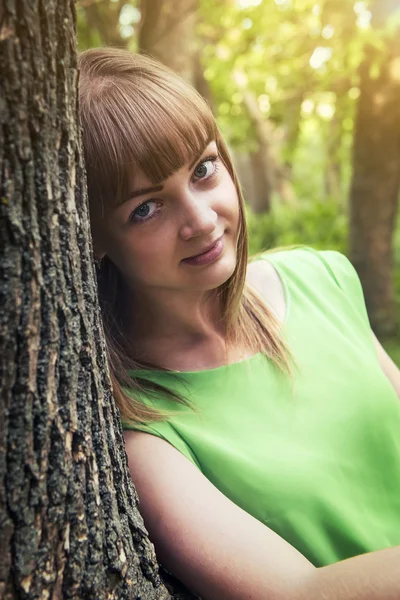 Jeune fille sensuelle appuyée contre un arbre — Photo