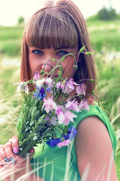 Menina sensual jovem cheirando um buquê de flores silvestres — Fotografia de Stock