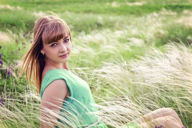 Genç seksi kız açık havada bir çim oturur