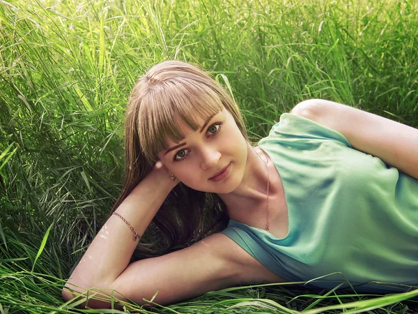 Jovem menina bonita deitada na grama — Fotografia de Stock