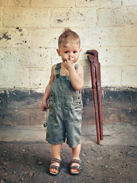 Niño pequeño con una llave inglesa de pie en la pared —  Fotos de Stock