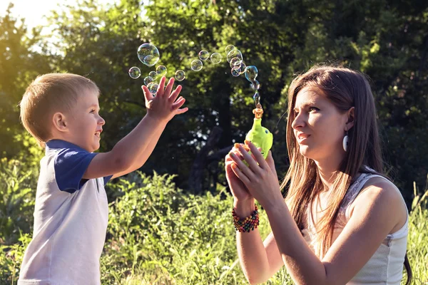 Boy playing catch soap bubbles outdoors — Stock Photo, Image