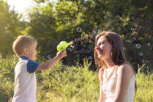 Boy playing catch soap bubbles outdoors