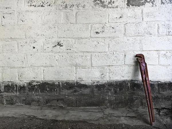 Старий регульований гайковий ключ, що стоїть на кам'яній стіні — стокове фото