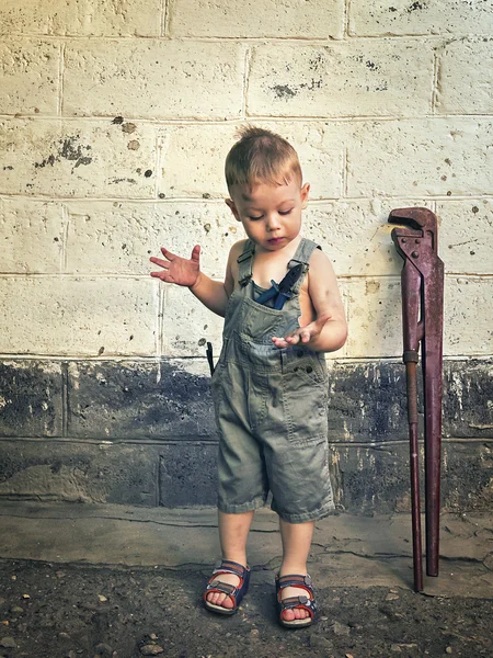 Little boy with a wrench standing at the wall — Stock Photo, Image