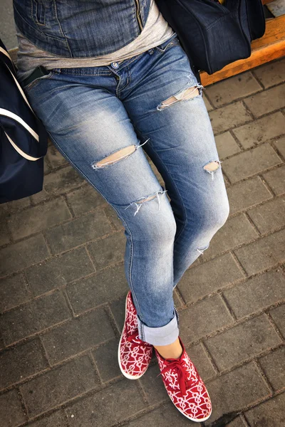 Girl in ripped jeans sitting on the bench — Stock Photo, Image