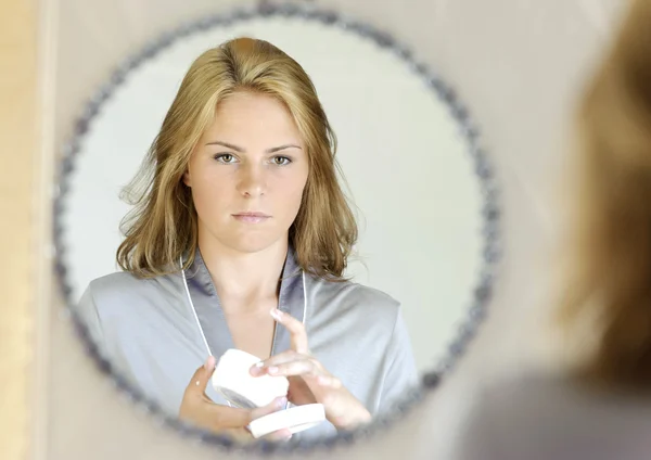 Beautiful young woman applying face cream — Stock Photo, Image