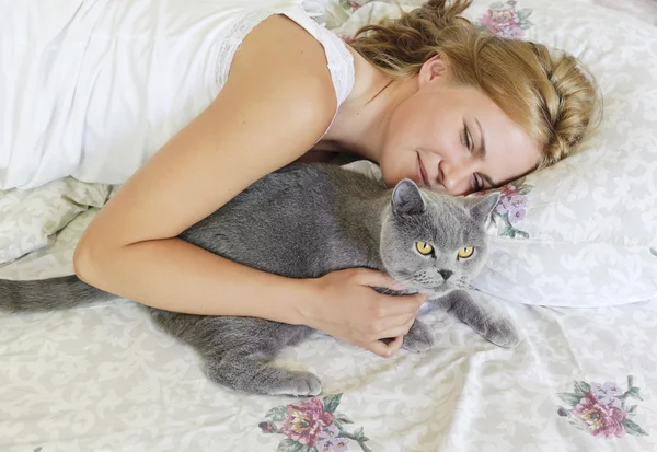 年轻漂亮的女人，与英国猫在床上 — 图库照片