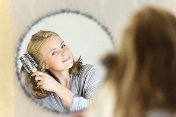 Belle jeune femme faisant des cheveux avec une brosse à cheveux — Photo