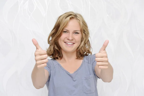 Mladá usměvavá žena ukazuje palec — Stock fotografie