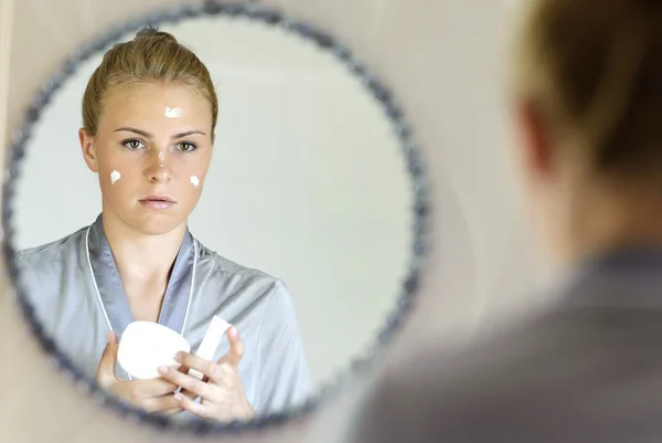 Belle jeune femme appliquant crème visage — Photo