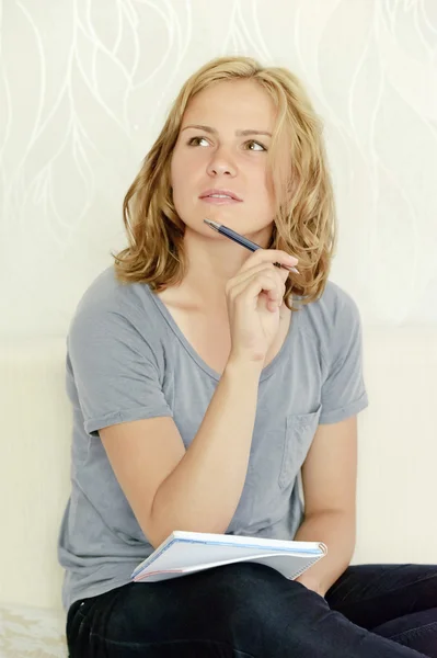 Jonge vrouw denken over het maken van aantekeningen in notitieblok Stockfoto