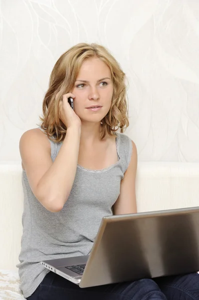 Junge Frau mit Laptop telefoniert — Stockfoto