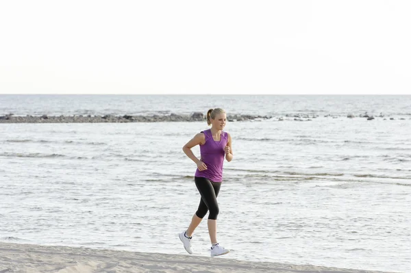 Young woman running along lake shore — Stock Photo, Image