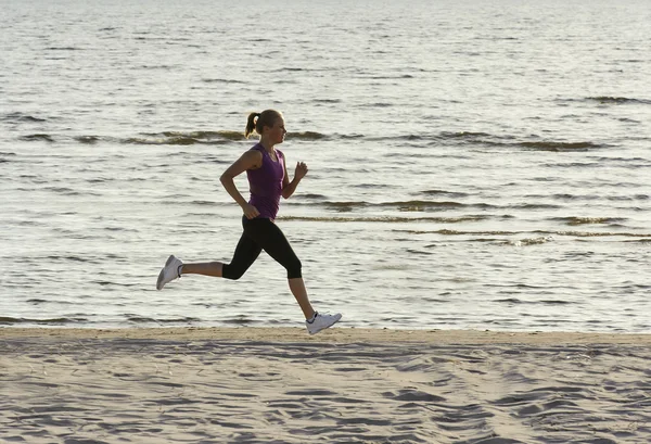 Young woman running along lake shore — Stock Photo, Image