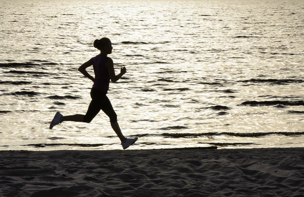 Ung kvinna löper längs sjöstranden — Stockfoto