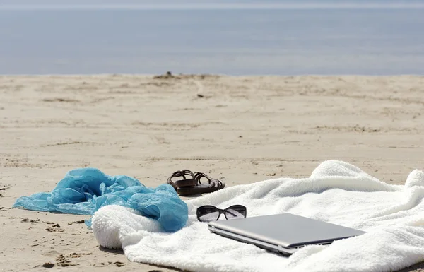 Обгортання, ноутбук, шарф і мули на пляжі — стокове фото