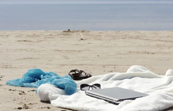 Wrap, Laptop, Schal und Pantoletten am Strand lizenzfreie Stockbilder