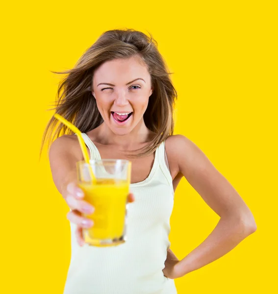 Menina adolescente bebendo suco de laranja no fundo amarelo — Fotografia de Stock