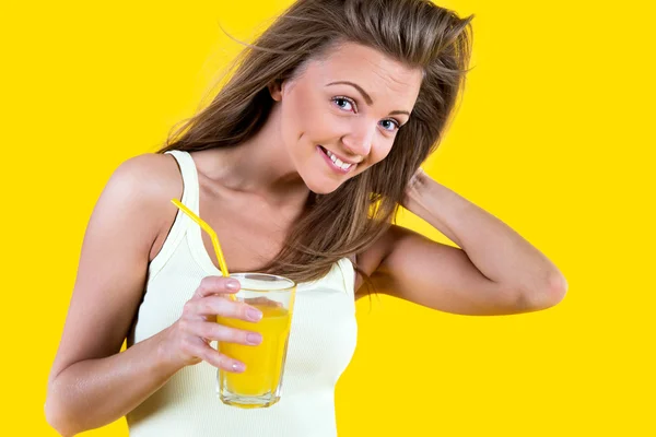 Teenager girl drinking orange juice on yellow background — Stock Photo, Image