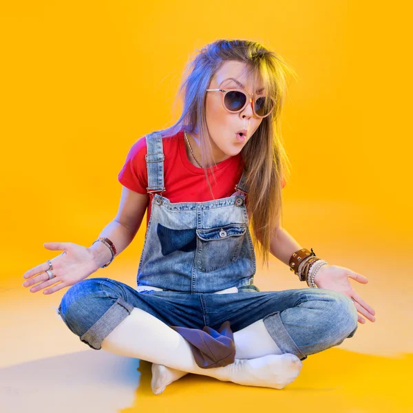 Retrato de chica divertida sentada con gafas sobre un fondo amarillo — Foto de Stock