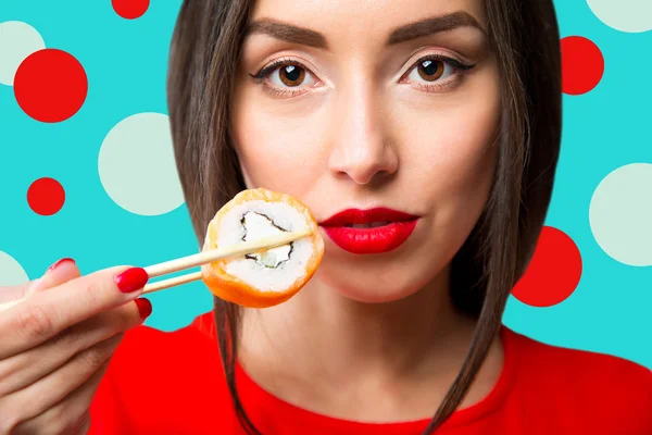 Jeune femme tenant des sushis avec une baguette, isolée sur bleu — Photo