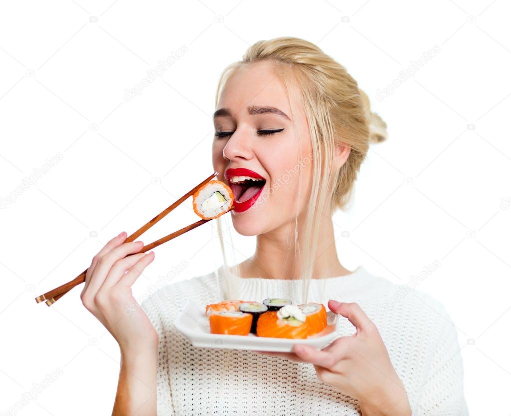 Young woman holding sushi with a chopsticks, isolated on white