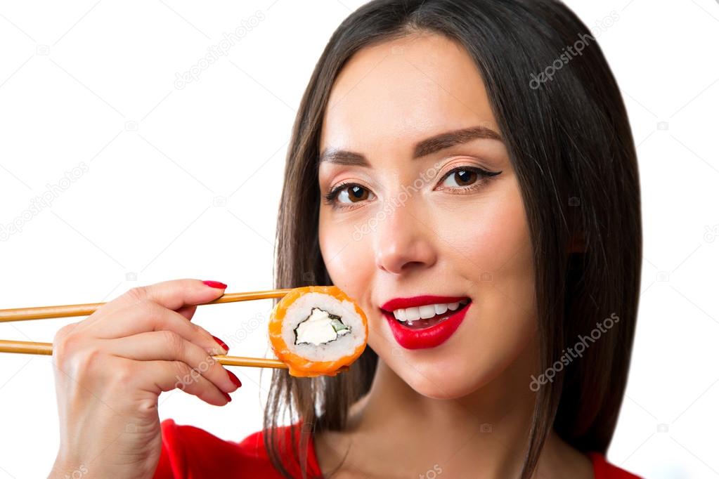 Young woman holding sushi with a chopsticks, isolated on white