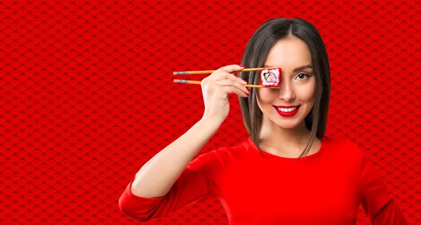 Mujer joven sosteniendo sushi con palillos, aislado en rojo — Foto de Stock