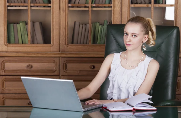 Menina trabalhando com laptop sentado na mesa no escritório — Fotografia de Stock