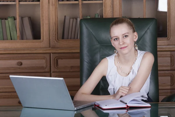 Chica trabajando con el ordenador portátil sentado en el escritorio de la oficina —  Fotos de Stock