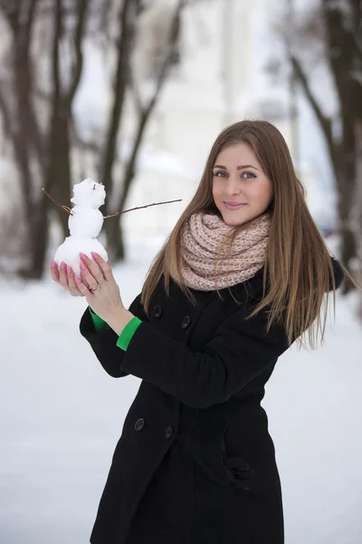 Meisje in zwarte jas met een sneeuwpop — Stockfoto