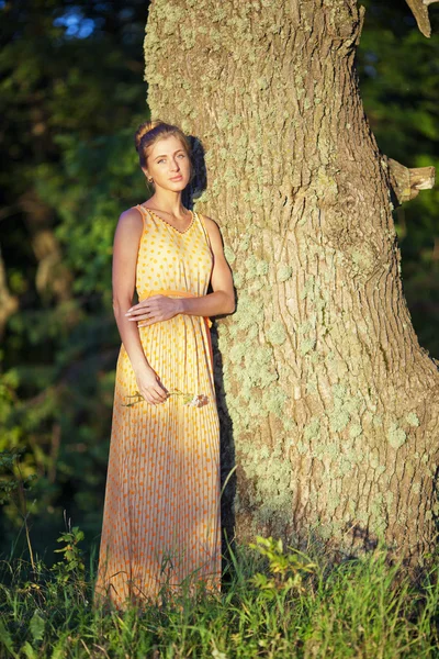Молодая девушка в желтом платье, стоящая у березы — стоковое фото