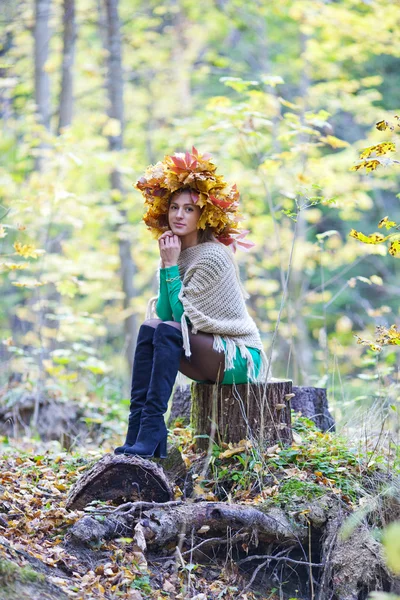 Kız sonbahar. Parkta bir kütük üstünde onun baş oturan yaprakların bir çelenk ile genç kız — Stok fotoğraf
