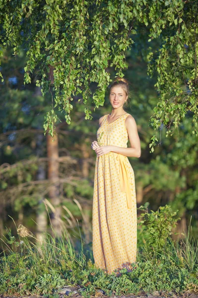 Niña en un vestido amarillo de pie en el abedul — Foto de Stock