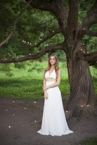 Selamat datang di cerita! Potret seorang gadis cantik berdiri di dekat pohon di mana lilin ditempatkan — Stok Foto