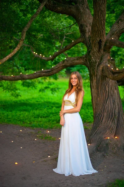 Bienvenido a la historia! Retrato de una hermosa niña de pie junto al árbol en el que se colocan velas — Foto de Stock
