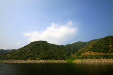 Tepeler ve mavi bulutlu gökyüzü ile yeşil lndscape