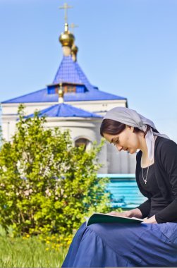 Woman reading an orthodox book clipart